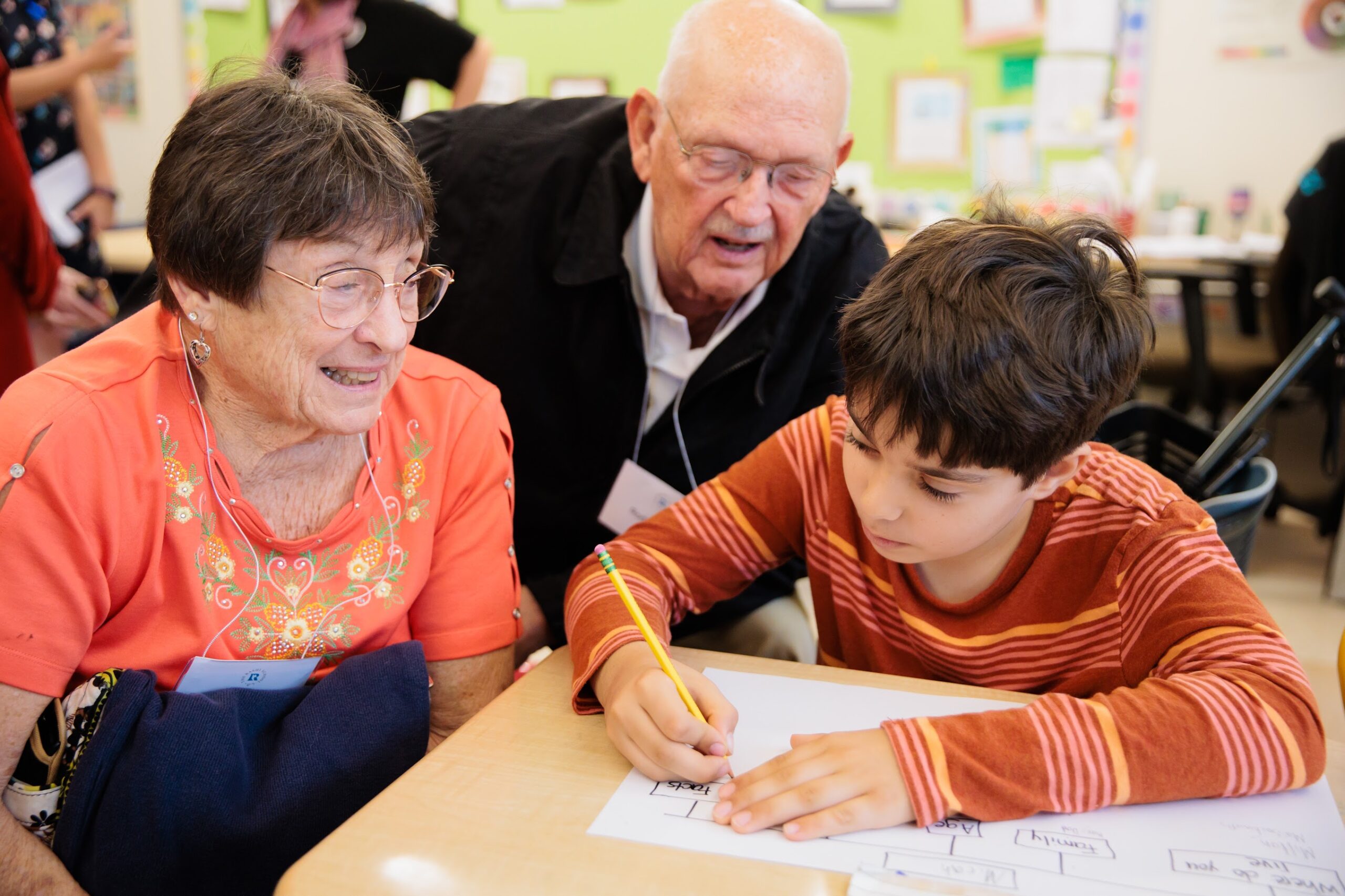 an elementary school student does a classroom assignment with grandparents