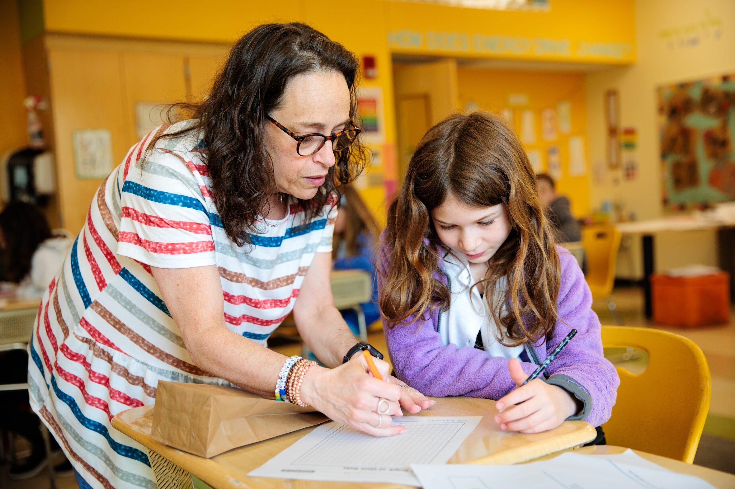 An elementary school student works with a teacher during class