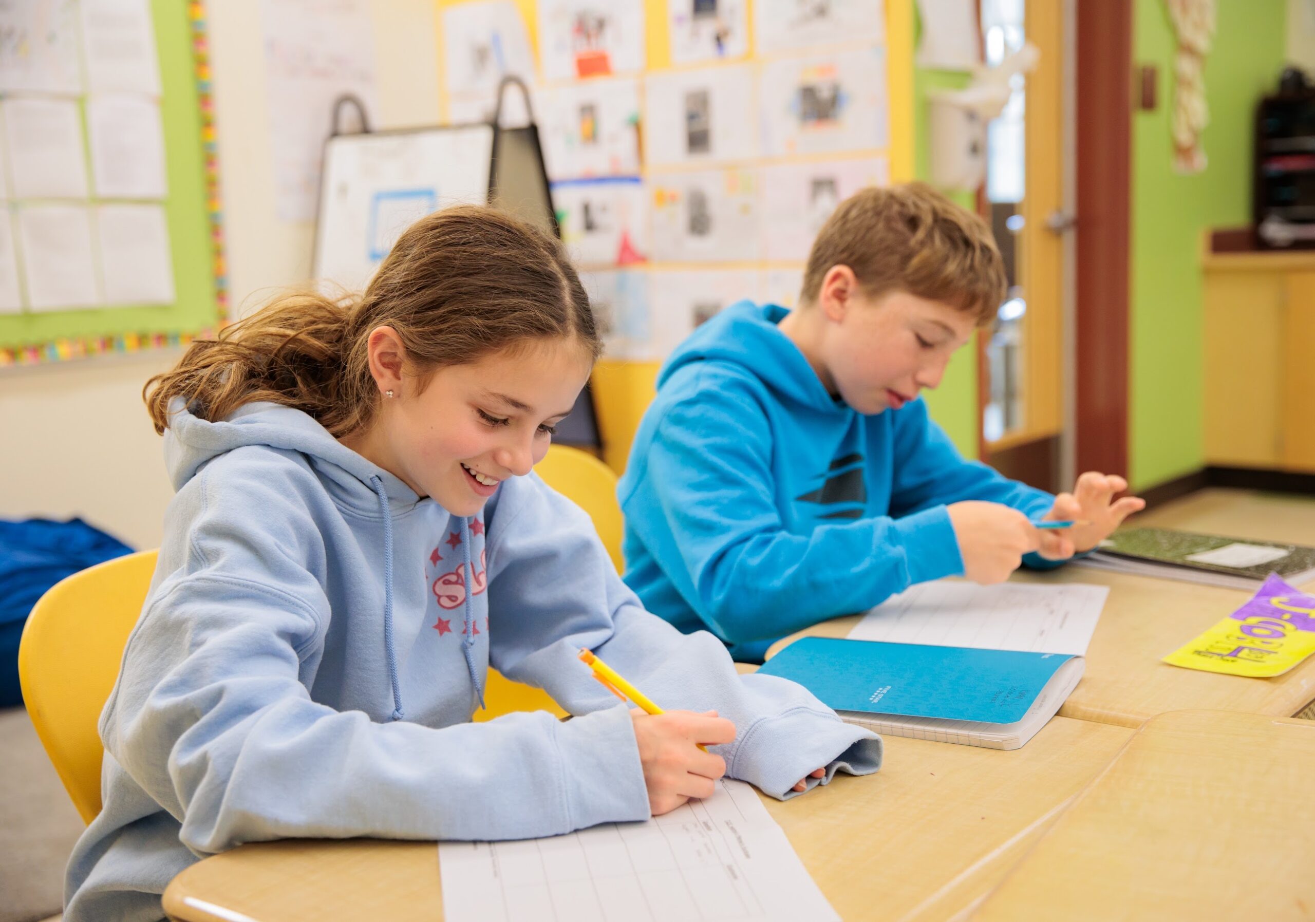 Two elementary school students complete a math problem on a worksheet in the classroom